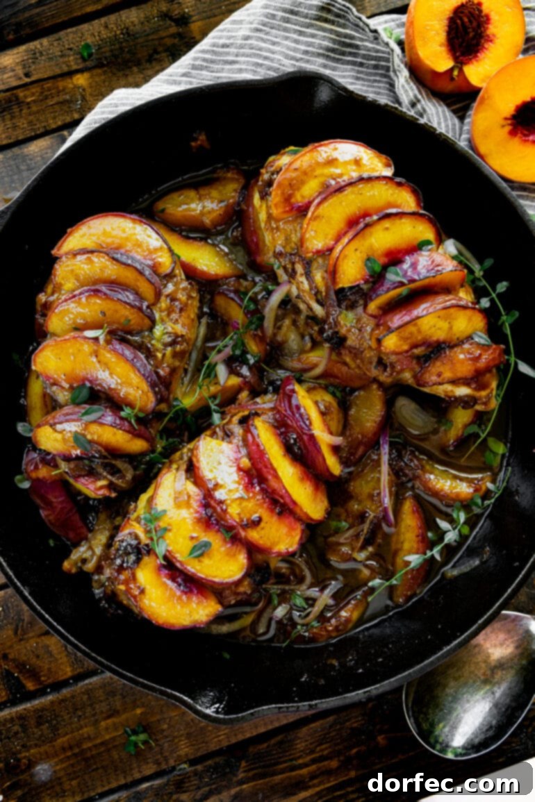 Sweet and Savory Peach Chicken 2 A large cast-iron skillet featuring three perfectly cooked chicken breasts, each generously topped with glistening sliced roasted peaches.