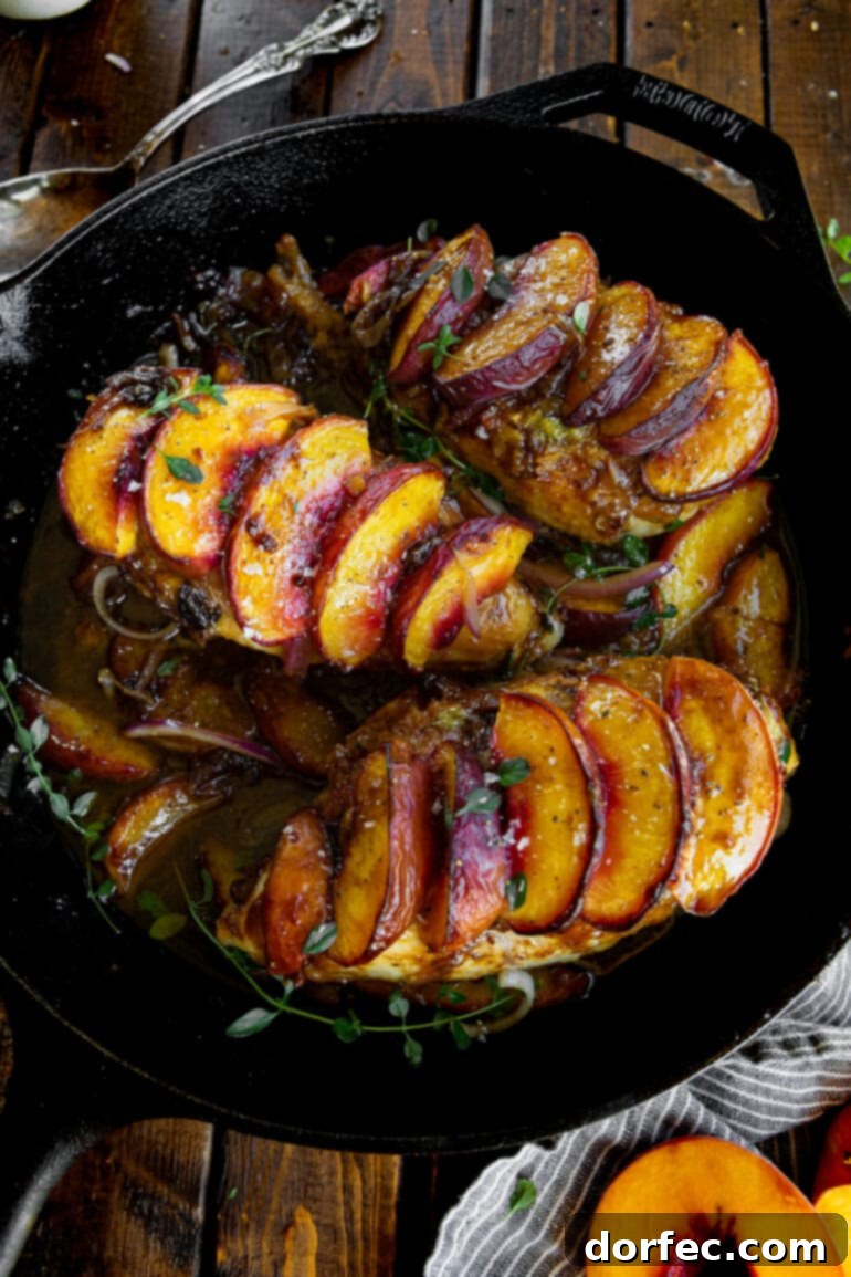 Sweet and Savory Peach Chicken 5 A cast-iron skillet presenting three golden, juicy chicken breasts, each adorned with sweet roasted peach slices, all bathed in a flavorful pan sauce.