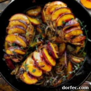 A large cast-iron skillet with three chicken breasts in it, each covered in sliced peaches.