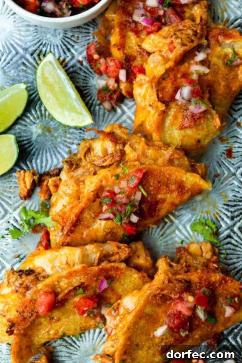 A tantalizing photo of several birria chicken tacos, featuring crispy, cheesy shells filled with savory shredded chicken, beautifully garnished with fresh pico de gallo on a sleek metal tray, ready for dipping.
