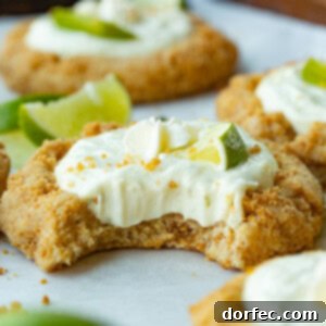 A golden baked graham cracker cookie filled with key lime pie filling and topped with a small lime wedge and a dollop of whipped cream