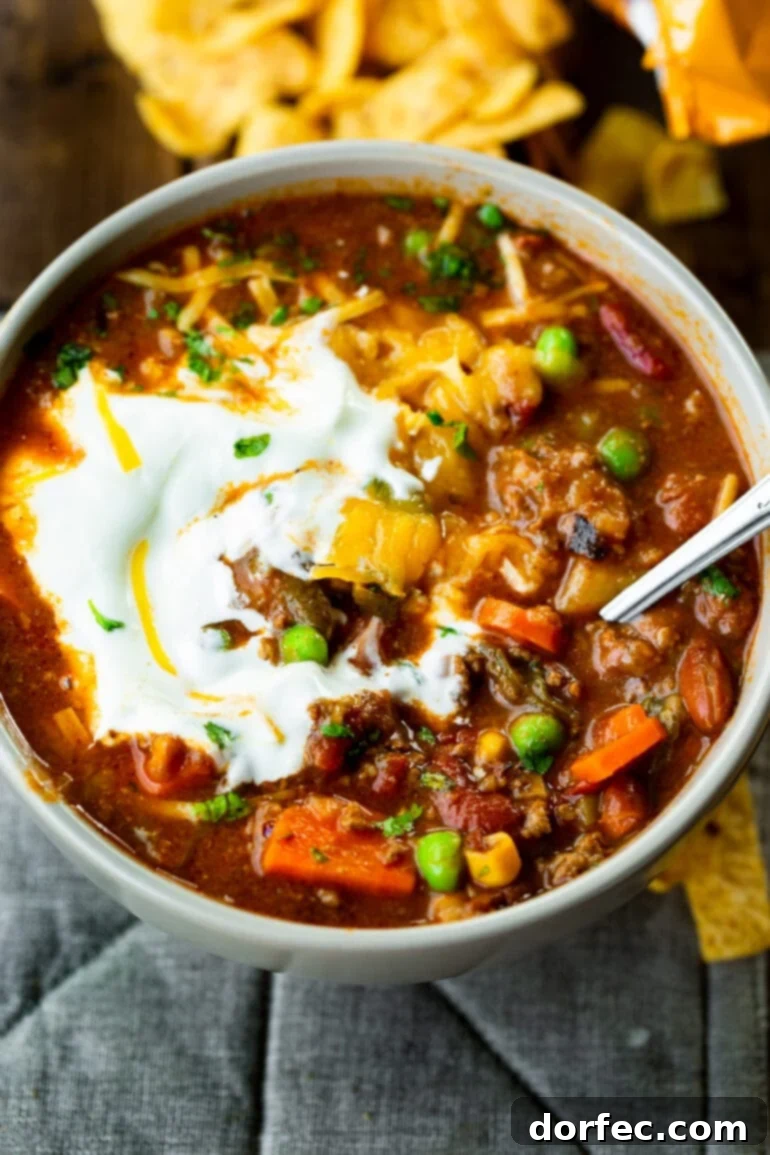 A close-up photo of a steaming bowl of delicious taco stew, generously topped with a swirl of creamy sour cream and a sprinkle of shredded cheddar cheese, ready to be enjoyed.