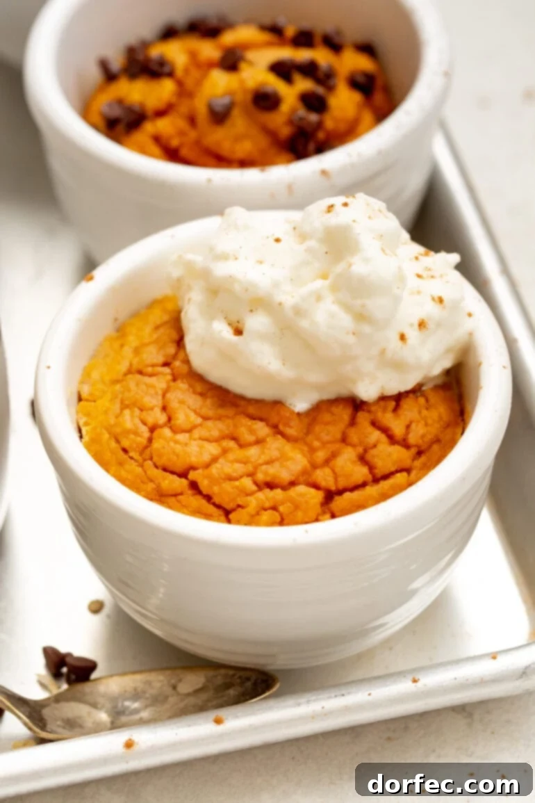 A photo of a pumpkin mug cake baked and topped with a dollop of whipped cream, ready to be enjoyed.