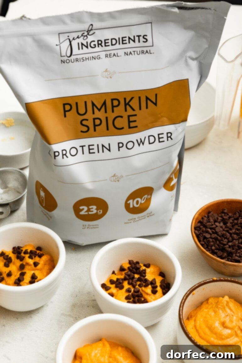 A photo of a bag of Just Ingredients pumpkin spice protein powder surrounded by unbaked pumpkin mug cakes, highlighting a key ingredient.
