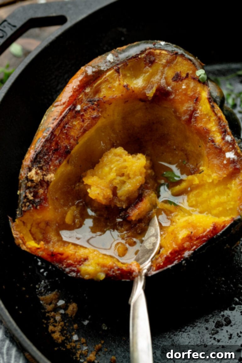 A photo taken over the top of a halved acorn squash that has been roasted and topped with brown sugar and butter, ready to be served.