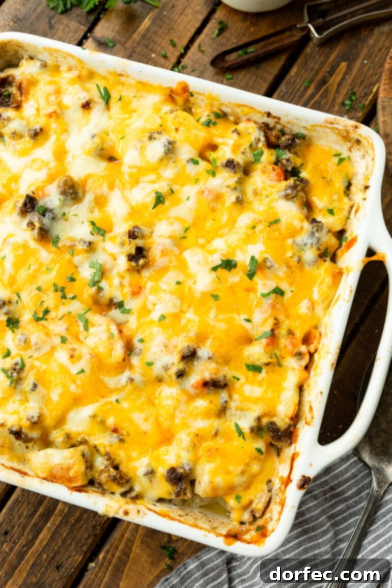 A rectangular baking dish filled to the brim with cheesy hamburger potato casserole, golden brown and bubbling with melted cheese. 