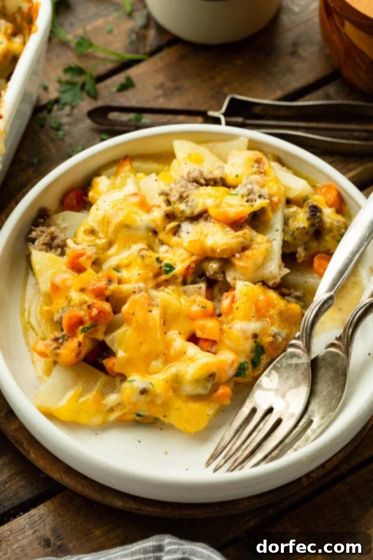 A beautifully plated serving of cheesy ground beef and potato casserole, accompanied by two forks, inviting you to dig in. 