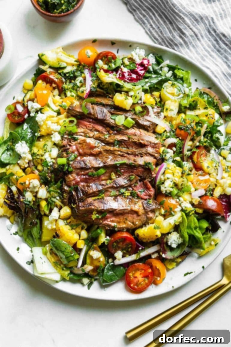 a photo of a large white plate full of a grilled steak and gorgonzola salad topped with grilled corn and gorgonzola cheese.