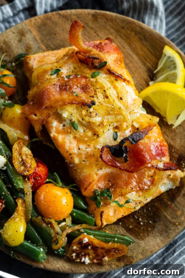 a photo of a baked salmon filet wrapped in two strips of bacon and glazed with a mustard maple sauce