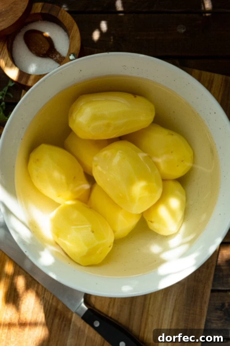 A bowl filled with peeled whole Yukon Gold potatoes, submerged in fresh water, preparing for their transformation into creamy Instant Pot mashed potatoes.
