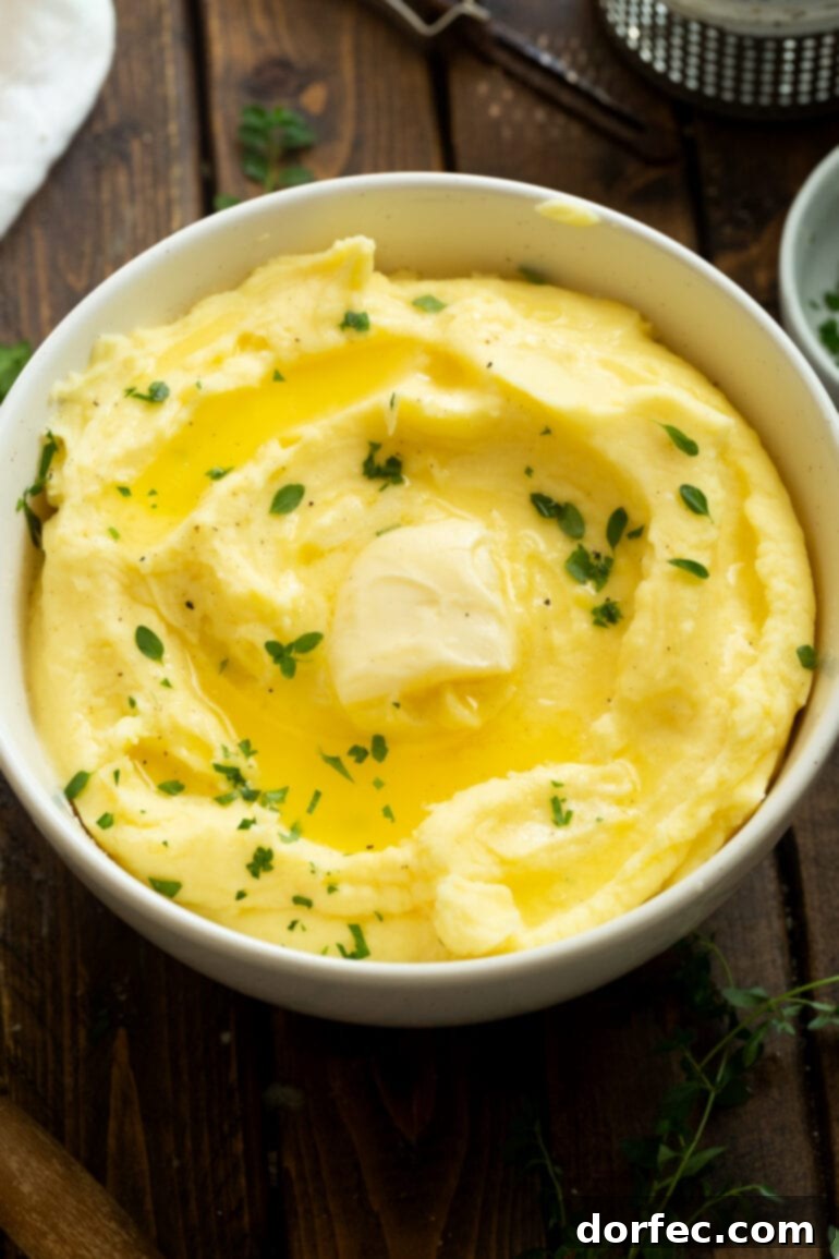 A rustic bowl filled with rich, buttery mashed potatoes, generously topped with fresh green herbs and a melting pat of butter, making it an irresistible centerpiece for any holiday or family meal.