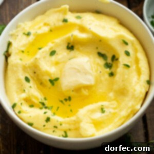 A bowl full of buttery mashed potatoes topped with fresh herbs and melting butter, a perfect side dish for any occasion.