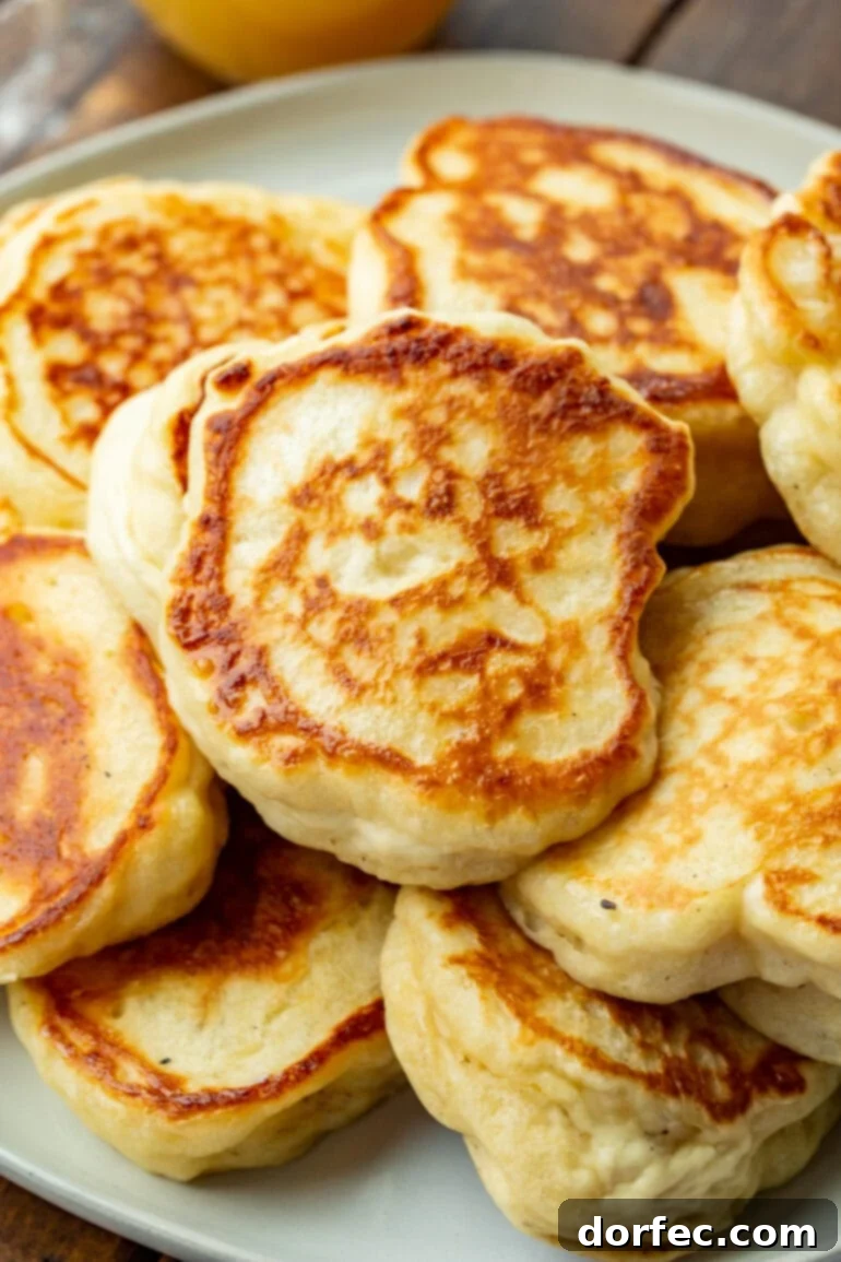 A photo showcasing several golden, crispy Oladi pancakes piled artfully on a white serving plate, inviting you to indulge in their fluffy goodness.