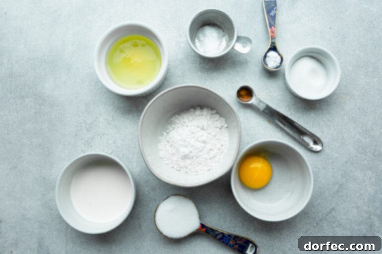 Fluffy Japanese Soufflé Pancakes 4 A beautifully arranged photograph showcasing all the essential ingredients required for making Japanese pancakes. Separate small bowls hold the bright egg yolks, pristine egg whites, finely sifted flour, granulated sugar, and fragrant vanilla extract, highlighting their freshness and readiness for preparation.