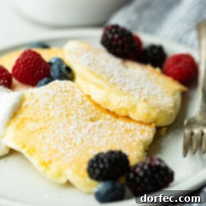 Fluffy Japanese Soufflé Pancakes 9 a photo of three fluffy Japanese cloud pancakes topped with powdered sugar and mixed fresh berries