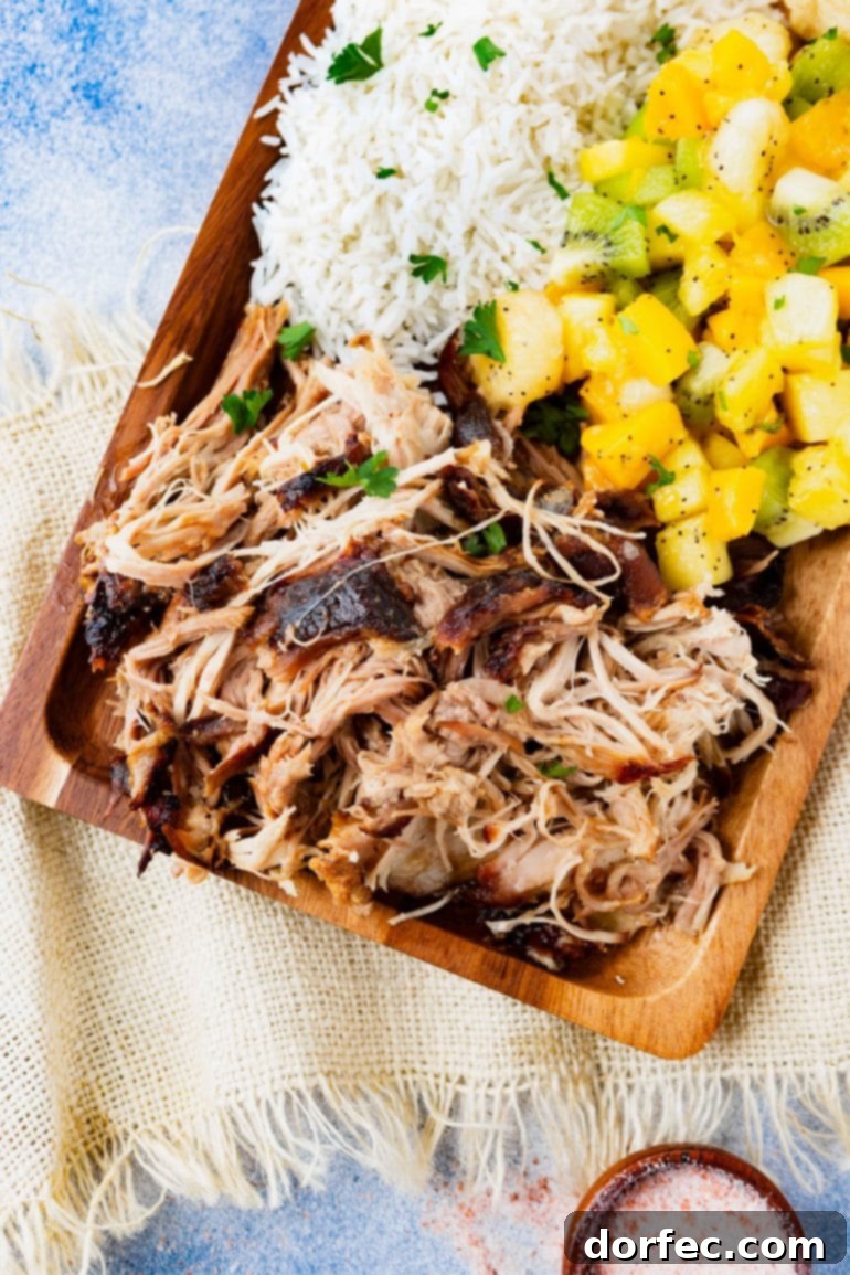 Weekly Meal Plan October 23-29 4 a photo of a rectangular wooden platter full of kalua pulled pork, herbed rice, tropical fruit salad and golden Hawaiian rolls.