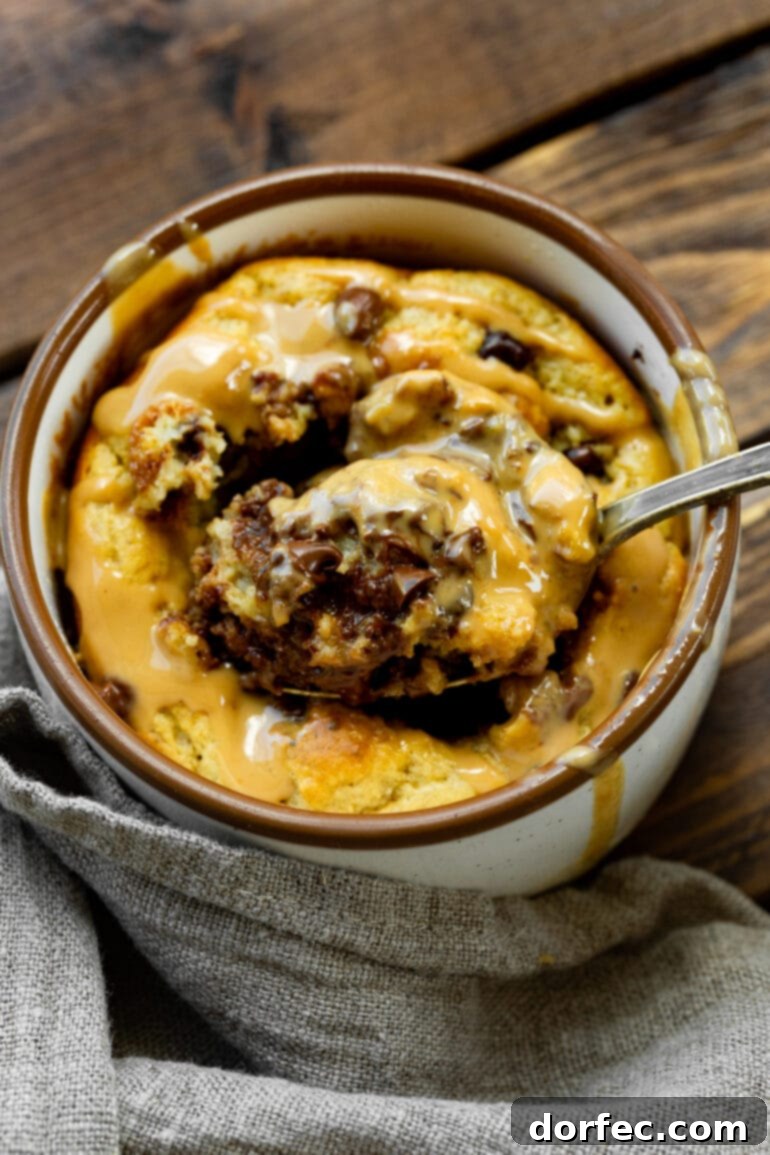 Weekly Meal Plan October 23-29 8 a photo of a mug full of baked oatmeal peanut butter and chocolate mug cake and someone is removing a spoonful of cake from the middle.