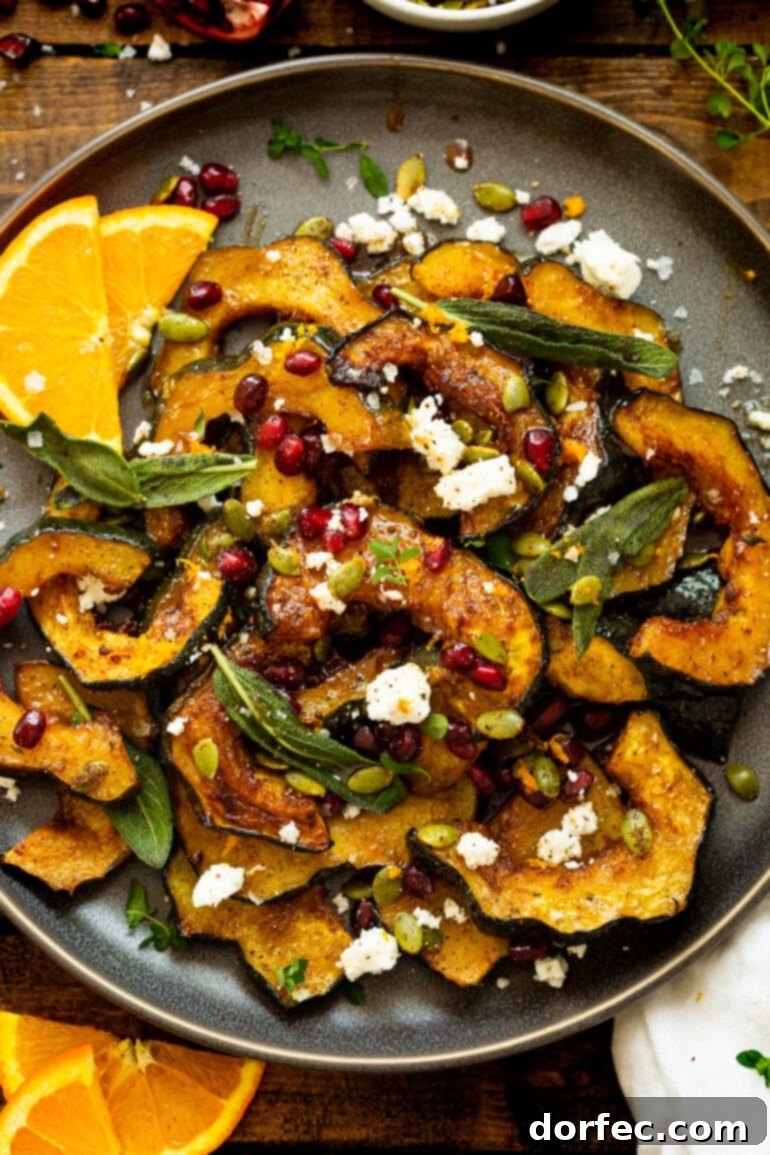 Heartwarming Holiday Acorn Squash 2 Slices of roasted acorn squash topped with vibrant pomegranate seeds, crumbled feta, fried fresh sage, toasted pepitas, and fresh thyme, beautifully arranged on a serving plate.