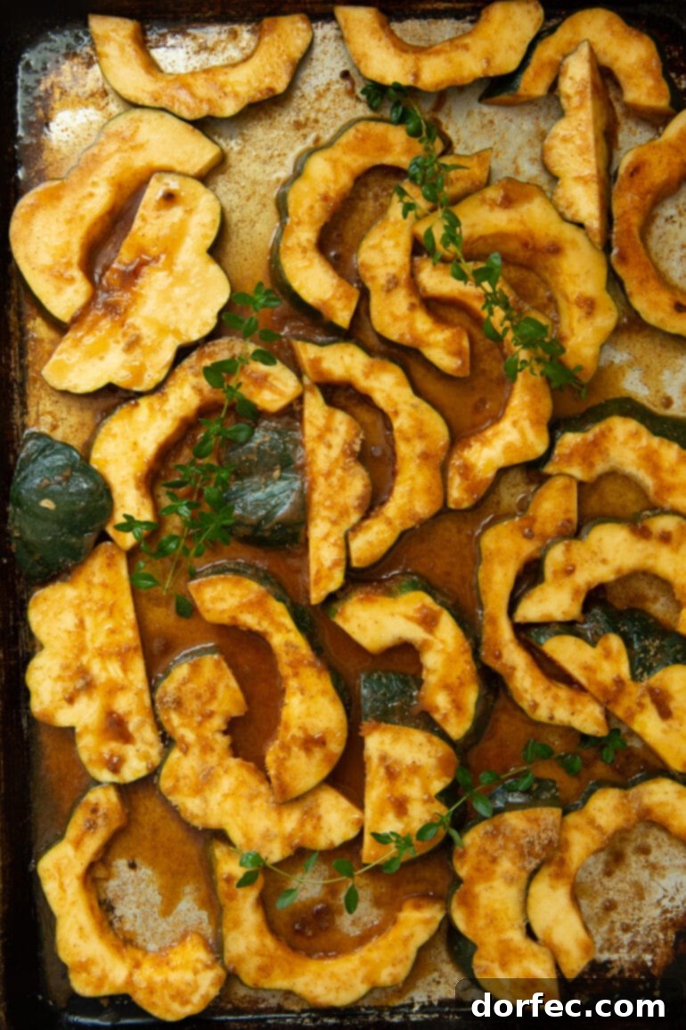 Heartwarming Holiday Acorn Squash 8 A baking sheet filled with uncooked acorn squash slices, beautifully coated in a rich seasoning mixture, ready for roasting.