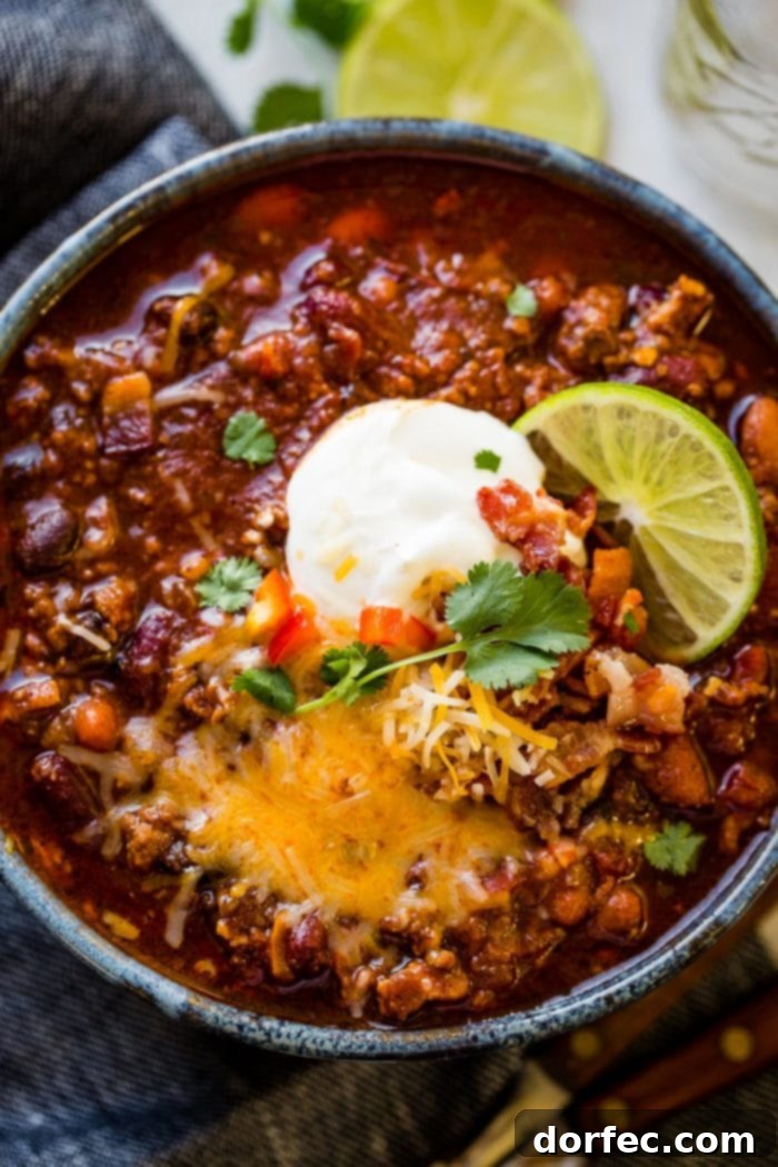 A delicious bowl of award-winning Instant Pot Chili, generously garnished with shredded cheese and fresh green onions, perfect for a cozy Halloween dinner or a chili cook-off.