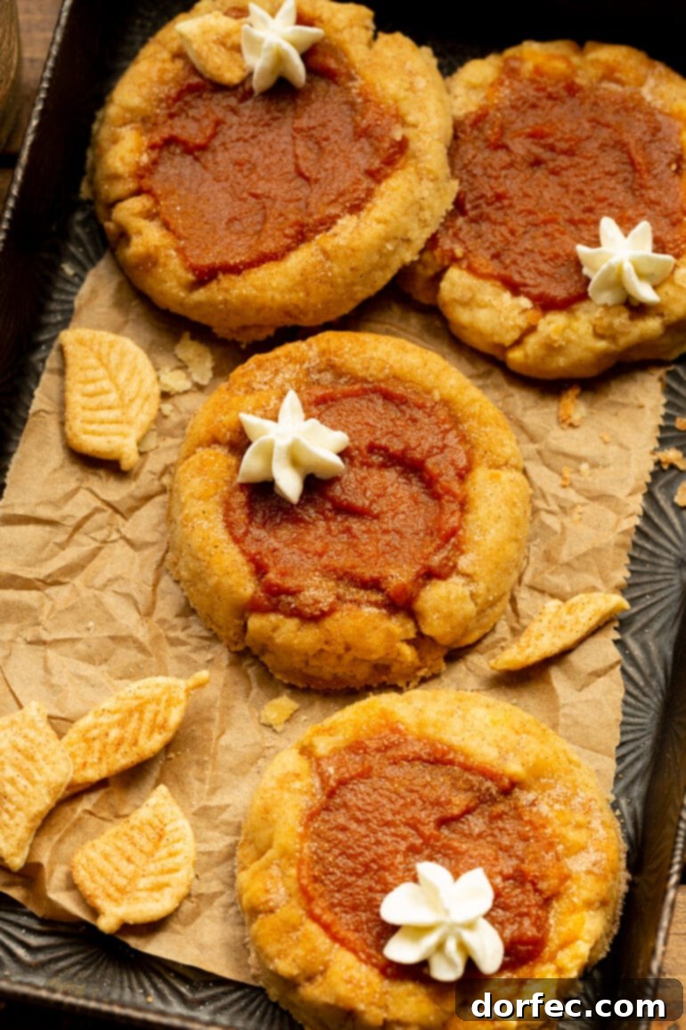 Delightfully Soft Chewy Pumpkin Pie Spice Cookies 5 A warm, inviting close-up of several baked pumpkin pie cookies, showing their golden-brown edges and perfectly set pumpkin filling, resting on a sheet of crumpled parchment paper.