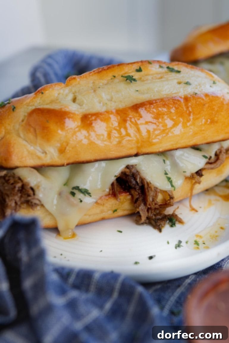 This Week's Menu Plan Nov. 13 to 19 5 A perfectly assembled French Dip Sandwich on a hoagie roll, filled with tender beef and melted cheese, served on a plate with a blue and white napkin.