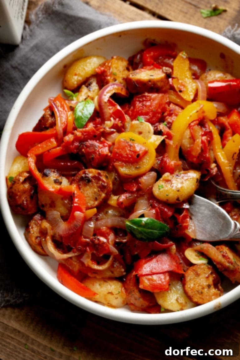 This Week's Menu Plan Nov. 13 to 19 6 A large white bowl overflowing with succulent sausage and brightly colored bell peppers mixed with soft gnocchi, creating a hearty and inviting meal.