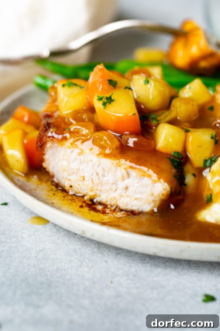 This Week's Menu Plan Nov. 13 to 19 9 A perfectly cooked, juicy pork chop topped generously with a vibrant, chunky apple chutney, with a cross-section visible showing the tender interior.