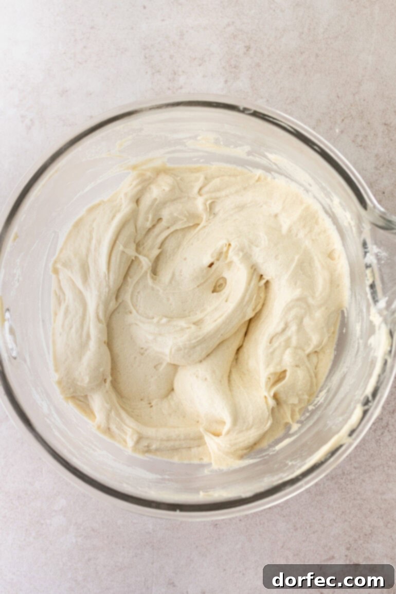 a photo taken over the top a large glass bowl of cream cheese frosting