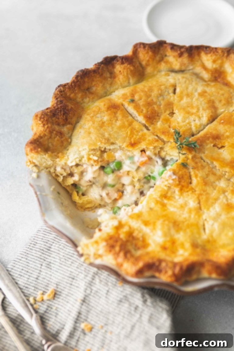 Effortless Weekly Menu November 20 to 26 9 A mouth-watering photo of a freshly baked turkey pot pie, with a perfect slice carefully removed, revealing the rich, creamy interior brimming with tender turkey pieces, vibrant green peas, and sweet orange carrots, all encased beneath a golden, flaky crust.