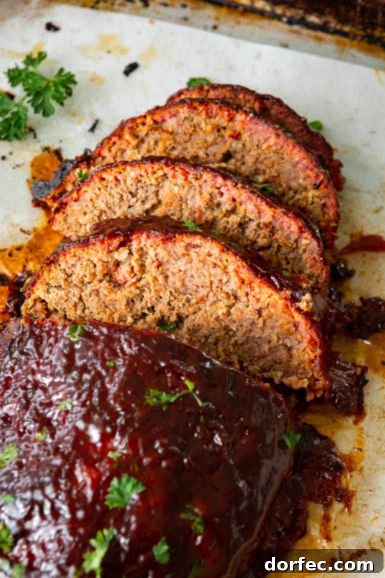 A photo of a smoked meatloaf taken from overhead with three slices cut off one end, showing a beautiful smoke ring and garnished with chopped fresh parsley.