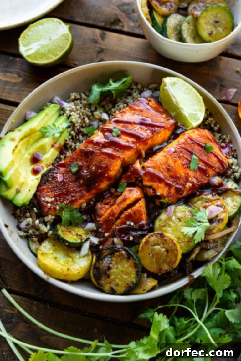 Tender Smoky Air Fryer Salmon 6 A plate featuring two BBQ salmon fillets arranged on a bed of cooked quinoa, presenting a wholesome and appealing meal.