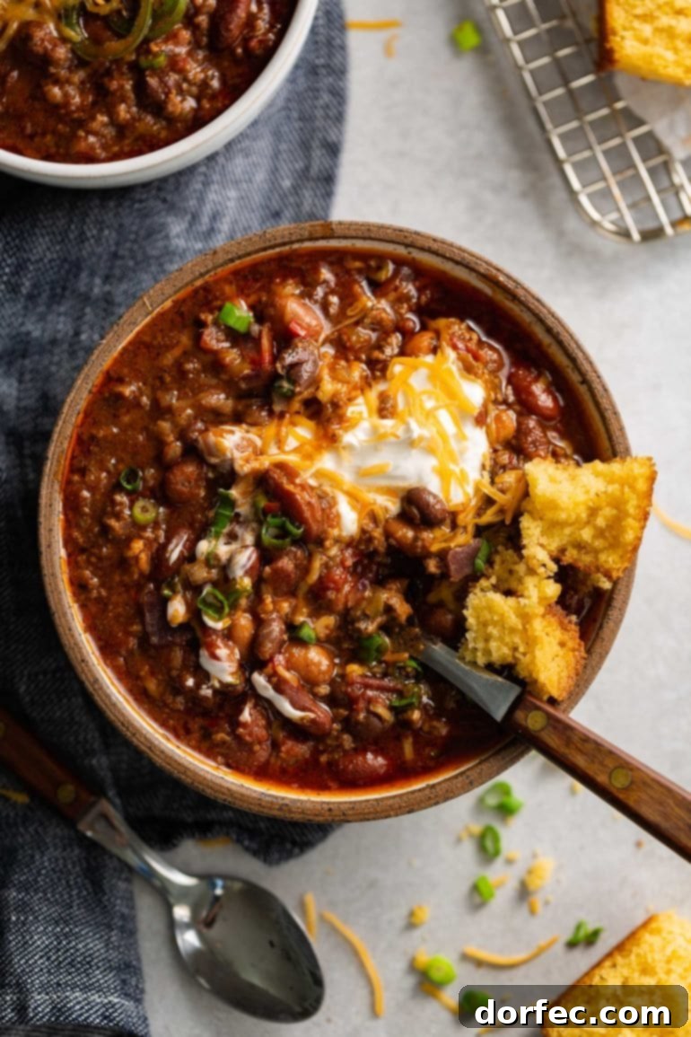 Weekly Meal Plan: December 11-17 7 A steaming, inviting bowl of the ultimate 'Best Chili,' brimming with savory ground beef, a rich mixture of beans, and a deeply spiced, robust sauce. It's lavishly topped with a generous dollop of creamy sour cream and a sprinkle of shredded cheese, with a spoon nestled in, ready for enjoyment.