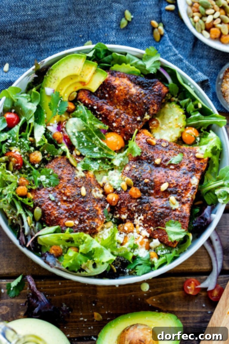 Weekly Meal Plan: December 11-17 8 A stunning and vibrantly presented serving bowl showcasing a bright, fresh arugula-cucumber salad, elegantly topped with three perfectly seasoned, golden-brown oven-baked salmon fillets. The dish is beautifully garnished with golden roasted chickpeas and a scattering of toasted pine nuts and pepitas, creating a visually appealing and wholesome meal.