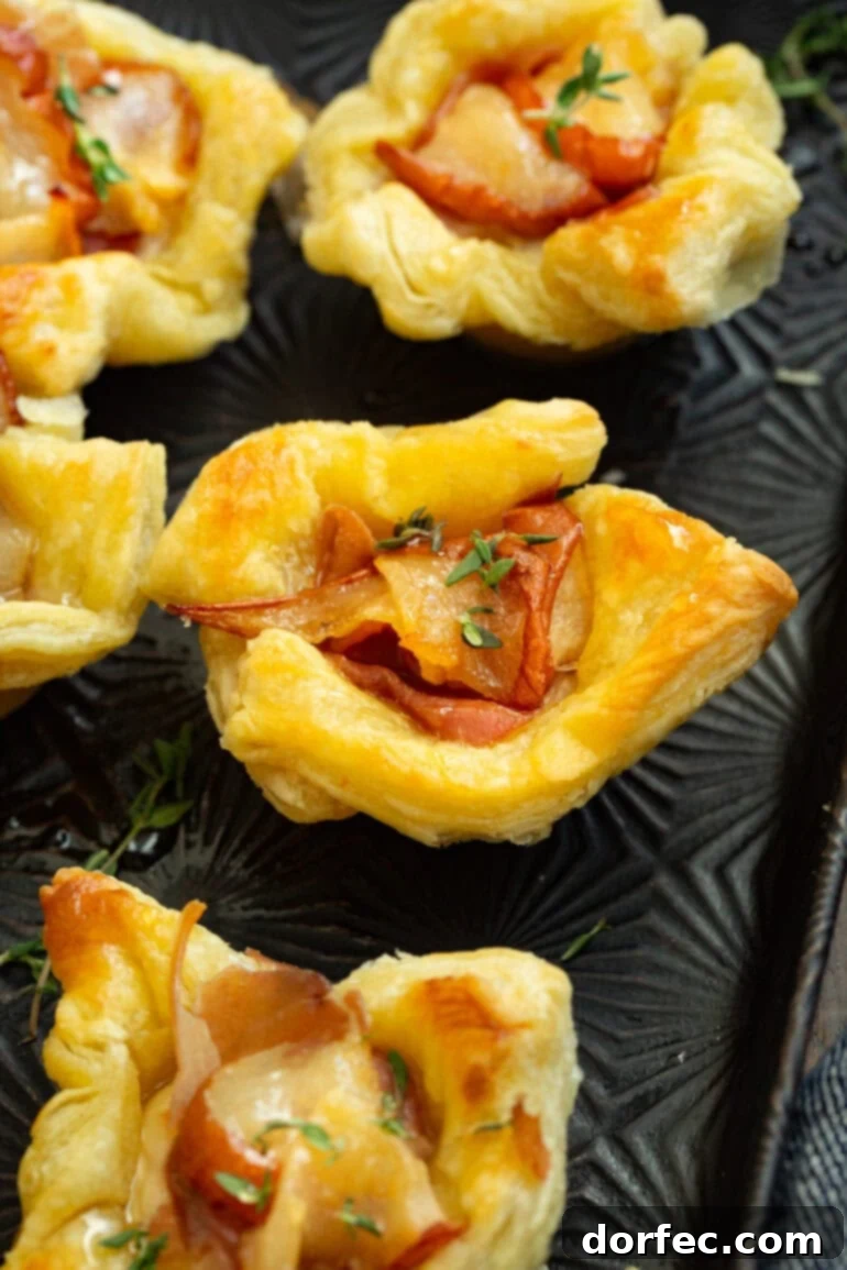 A photo of several puff pastry bites filled with roasted pear, prosciutto, thyme, and hot honey, ready to be served.