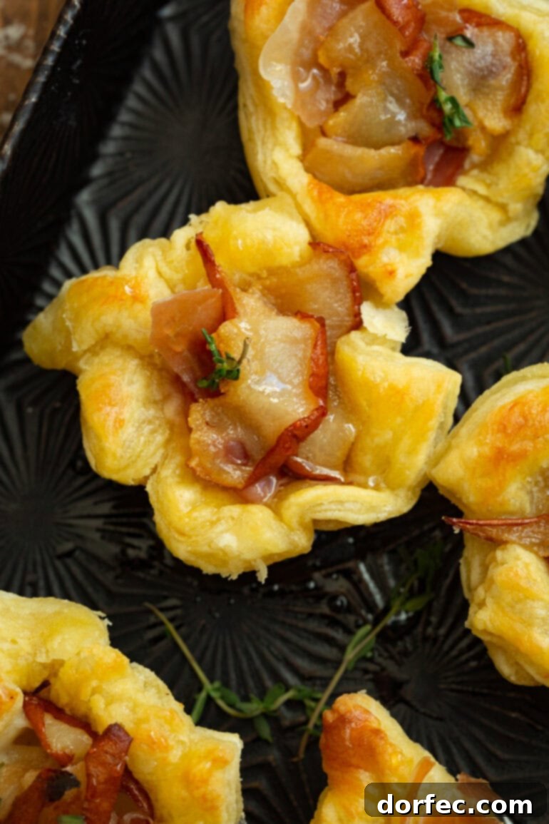 A photo of several golden-baked roasted pear and brie puff pastry bites arranged appealingly.