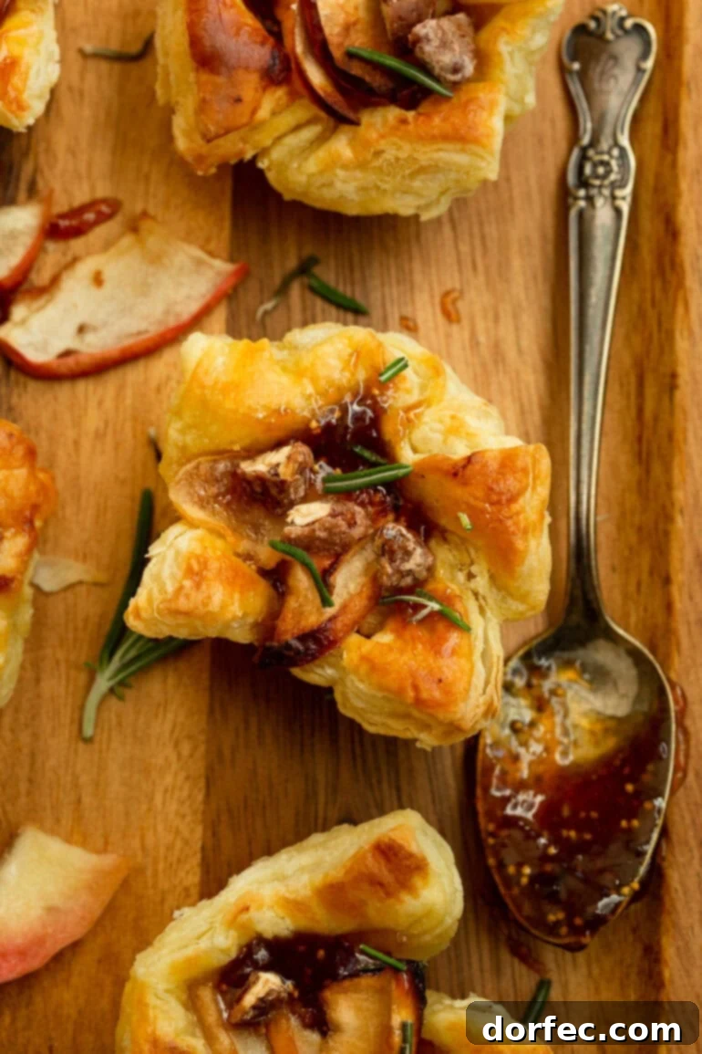 a photo of golden puff pastry topped with roasted apple slices, gooey brie, and sprinkled with chopped rosemary