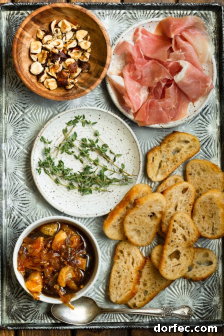Sweet and Salty Mandarin Prosciutto Crostini 3 An overhead view of all the fresh ingredients for mandarin and prosciutto crostinis, neatly arranged on a large silver tray, signaling readiness for preparation. Key ingredients like baguette, shallots, mandarin oranges, prosciutto, and herbs are visible.