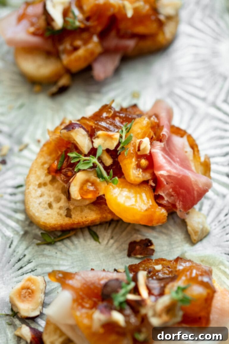 Sweet and Salty Mandarin Prosciutto Crostini 4 A perfectly assembled prosciutto and mandarin crostini, garnished with toasted hazelnuts and fresh thyme, showcased against a rustic backdrop, ready to be enjoyed as a savory appetizer.