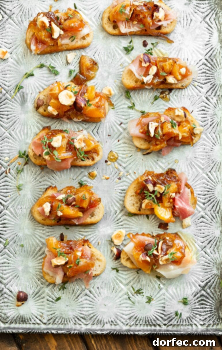 Sweet and Salty Mandarin Prosciutto Crostini 5 A sheet pan filled with several beautifully assembled crostinis, each topped with prosciutto, juicy mandarin oranges, sweet caramelized shallots, crunchy toasted hazelnuts, and fragrant fresh thyme, showcasing a batch ready to be served.