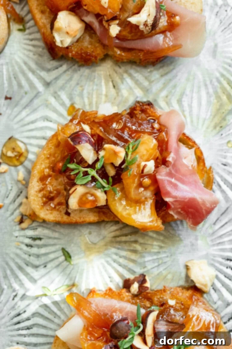 Sweet and Salty Mandarin Prosciutto Crostini 7 An overhead view of a single crostini topped with prosciutto, mandarin orange segments, caramelized shallots, crushed hazelnuts, and fresh thyme, showcasing its delicious layers and vibrant colors as a perfect appetizer.