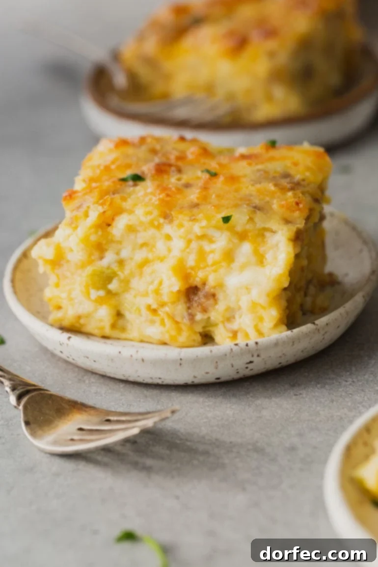 A hearty serving of fluffy Sausage and Monterey Jack Soufflé, rich with melted cheese and savory sausage bits, presented on a plate with a fork.