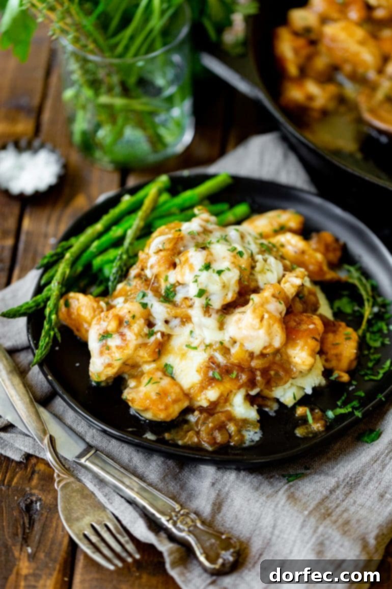 A plate of savory French onion chicken topped with melted Gruyère cheese, served with a side of fresh asparagus.