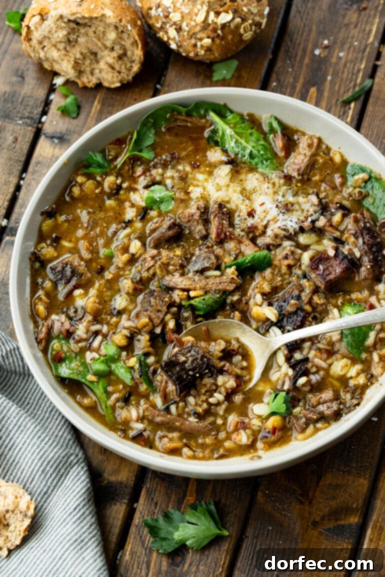 Weekly Meal Plan January 1-7 6 a photo of a bowl full of beef barley soup with chunks of tender beef, mushrooms, barley, wild rice, and spinach, highlighting a comforting and hearty meal.