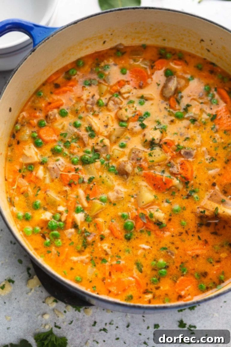 A large pot of rustic slow cooker chicken stew, filled with tender chicken pieces, vibrant vegetables, and fragrant herbs in a rich, reddish-yellow gravy.