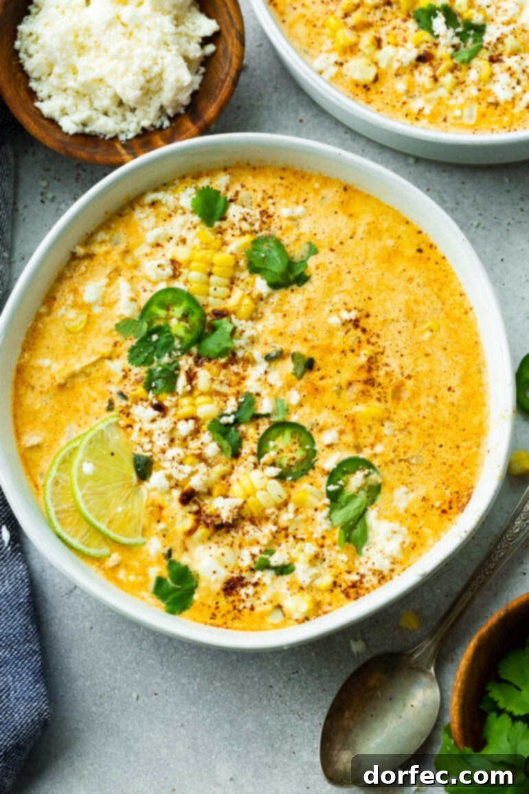 Elote Corn Soup 7 A beautiful, large bowl of Mexican Street Corn Soup, elegantly garnished with fresh lime wedges, vibrant chopped cilantro, thinly sliced jalapeño, and a generous sprinkle of crumbled Cotija cheese, highlighting its rich and inviting appearance.