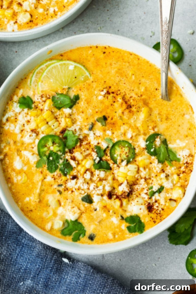 Elote Corn Soup 8 A close-up and appetizing photo of a large bowl of creamy Elote Corn Soup, beautifully topped with vibrant slices of jalapeño, fresh lime wedges, crumbled Cotija cheese, and chopped cilantro, ready to be enjoyed.