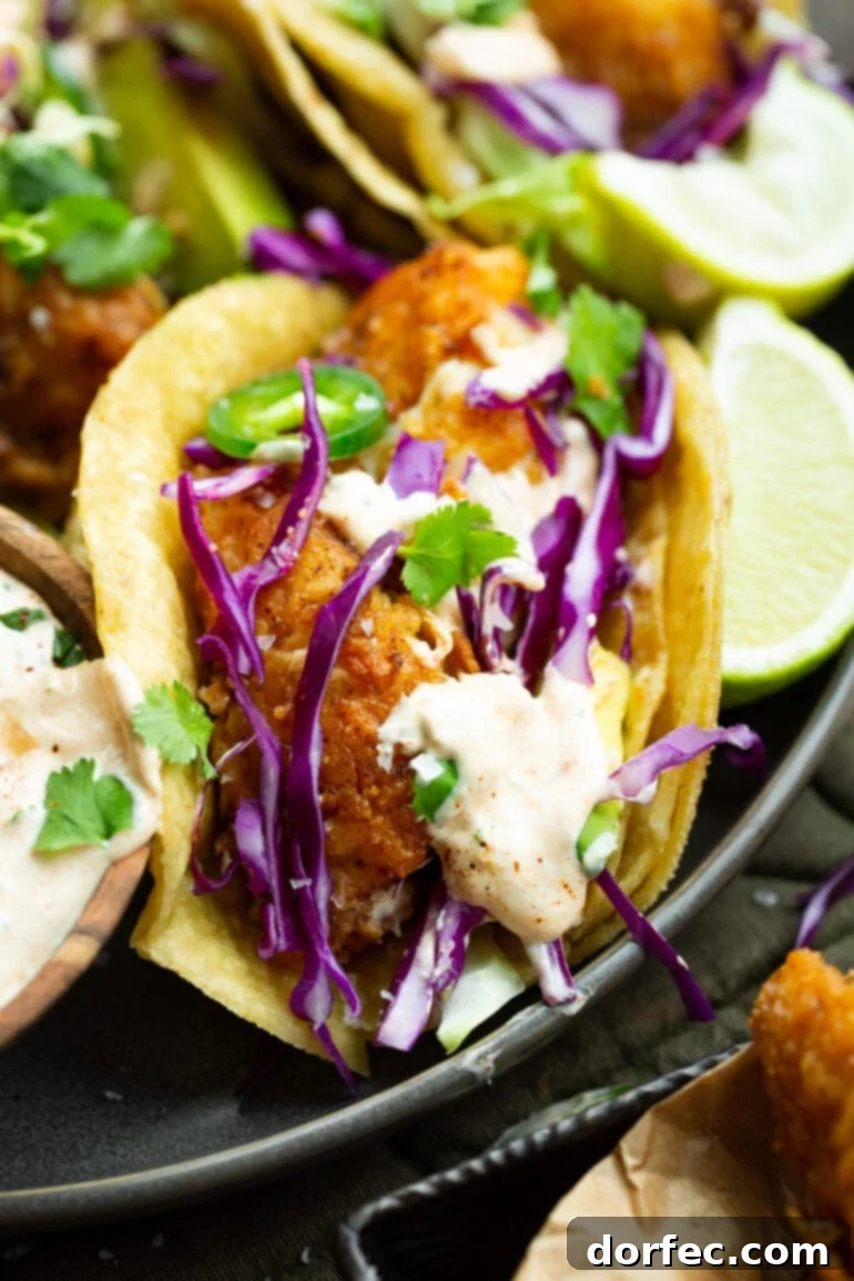 A close-up of a single, perfectly crafted fish taco resting in a soft corn tortilla, generously topped with shredded cabbage, vibrant jalapeño slices, and a rich, creamy sauce. The golden-brown pan-fried fish peeks out, promising a delightful bite.