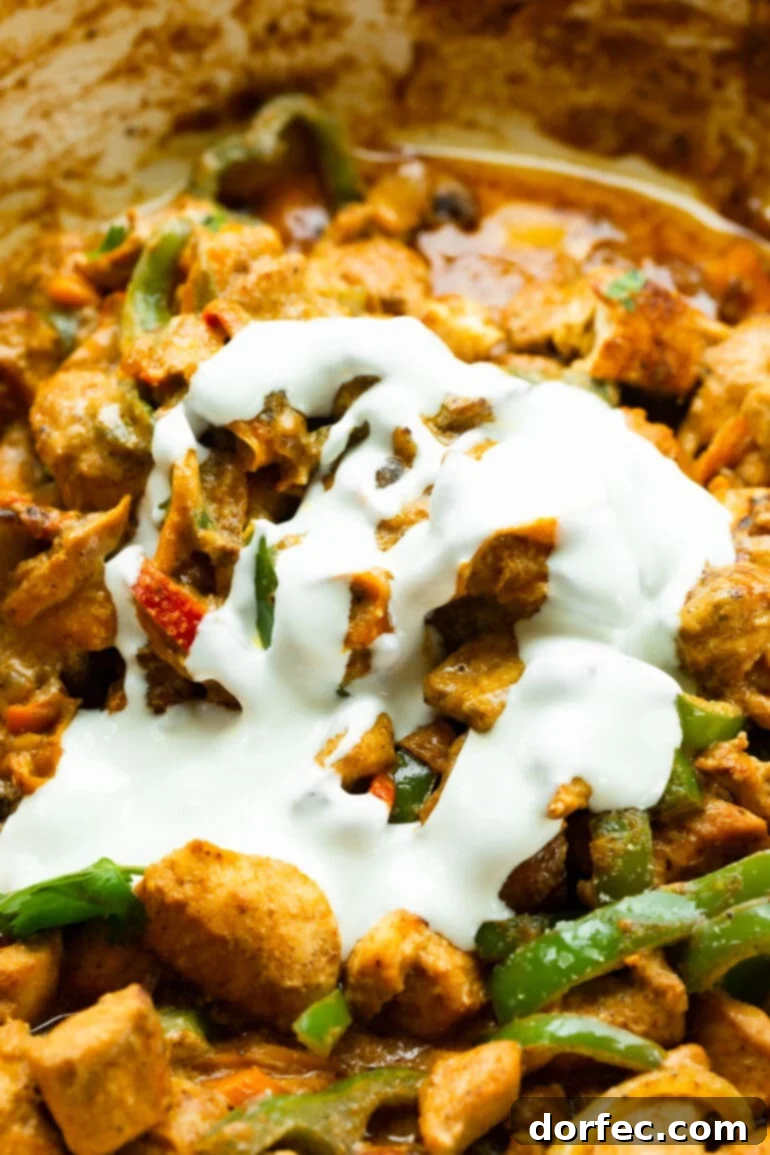A close-up photo of sauteed chicken chunks, colorful bell peppers, onions, and mushrooms generously topped with a rich, creamy sauce, ready to be served.
