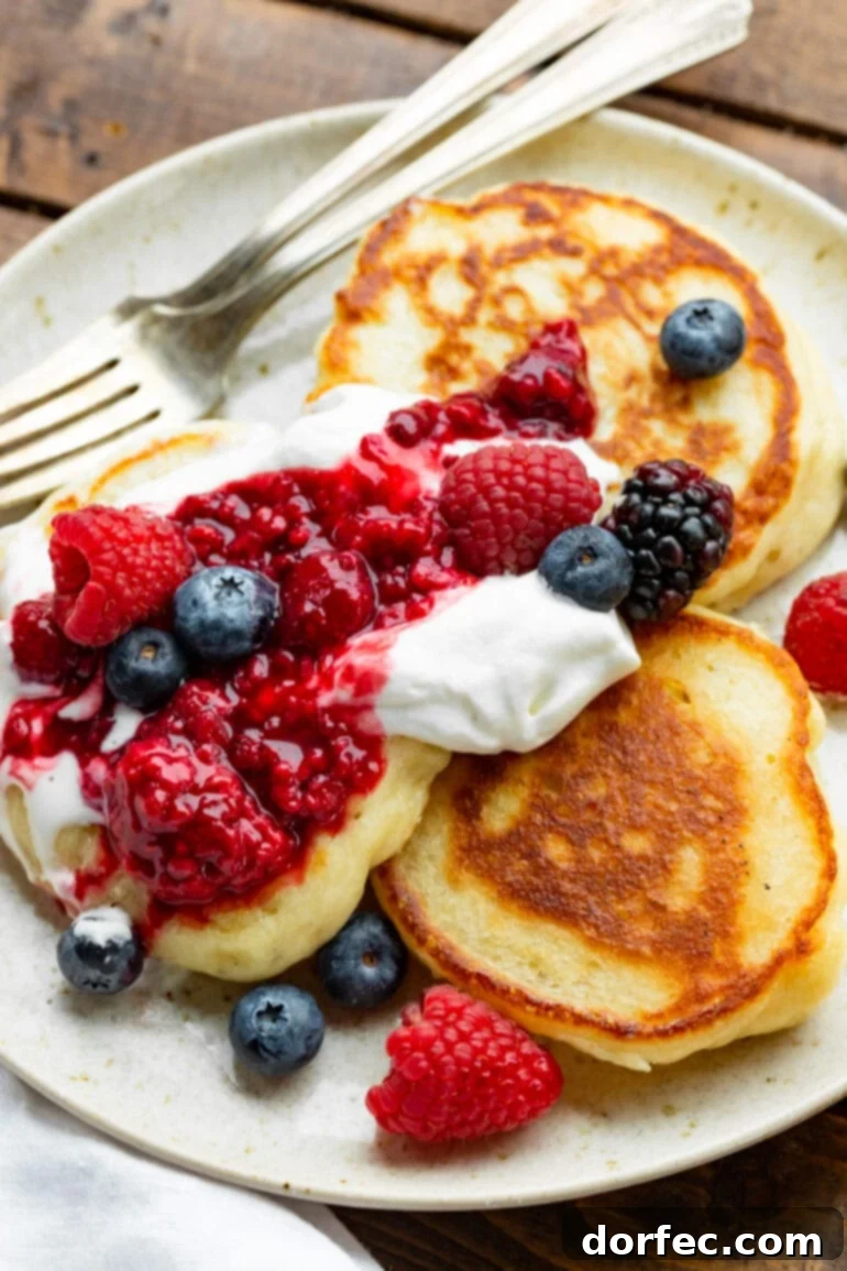 A stack of golden-brown, fluffy Ukrainian pancakes (Oladi) drizzled with syrup or honey, showcasing their inviting texture and delicious appeal.
